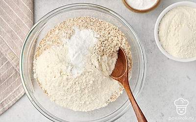 Пересыпьте получившуюся овсяную муку в глубокую миску. Всыпьте к ней разрыхлитель и пшеничную муку. Перемешайте.