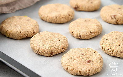 Разогрейте духовку до 180 °C. Застелите противень пекарской бумагой. Влажными руками, чтобы тесто не прилипало к пальцам, сформируйте круглые плоские печенья. Выкладывайте заготовки на пергамент на небольшом расстоянии друг от друга. Выпекайте 30 минут.