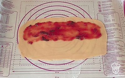 На пергаменте или силиконовом коврике раскатайте тесто в прямоугольный пласт. На одну половину выложите джем, не заходя на края. С помощью коврика закройте начинку свободной стороной теста и хорошо защипните края.