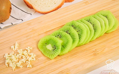 Нарежьте киви ломтиками толщиной 3-4 мм. Чеснок измельчите или выдавите через чеснокодавилку.