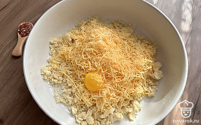 Добавьте натертый на мелкой терке сыр комнатной температуры. Отделите белок от желтка, добавьте желток к остальным ингредиентам. На этом этапе можно добавить в тесто любимые специи. Отлично подойдет сушеный чеснок или пряные травы. 