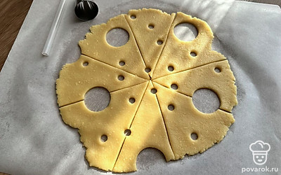 Тесто разделите на две равные части и раскатайте каждую в круглый пласт толщиной 5 миллиметров. Разрежьте на 8 треугольников, сделайте дырочки на сыре, вырезая кружочки разного диаметра.