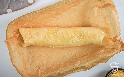 Сверните лаваш в рулет, подогнув края по бокам. Переложите в форму для запекания, застеленную пергаментом. Смажьте рулет растительным маслом и посыпьте кунжутом.