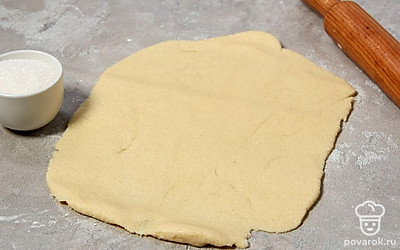 Присыпьте тесто отложенной мукой и раскатайте его в прямоугольный пласт толщиной 3-4 мм. На рабочую поверхность насыпьте сахар, положите на него тесто и сложите пласт пополам. Снова раскатайте тесто уже с сахаром, опять его сложите и еще раз раскатайте. Повторите все действия еще 2 раза. 