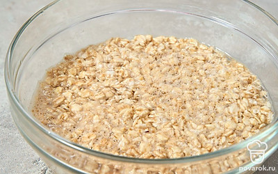 Всыпьте в небольшую емкость овсяные хлопья. Залейте их горячей водой. Перемешайте.