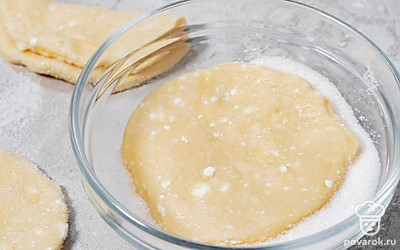 Насыпьте сахар в миску. Каждый кружочек теста обмакните одной стороной в сахар и сложите пополам сахаром внутрь.