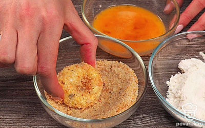 Приготовьте кольца в панировке. Смешайте в миске яйца с солью, тщательно перемешайте. В отдельную тарелку насыпьте муку, во вторую тарелку — панировочные сухари. Достаньте луковые кольца из морозилки. Обваляйте в муке, потом окуните в яичную смесь, затем обваляйте в сухарях. Положите в сковороду с хорошо разогретым маслом. Обжаривайте кольца по 2 минуты с обеих сторон до золотистого цвета. Готовые кольца переложите на бумажное полотенце, чтобы оно впитало лишний жир.