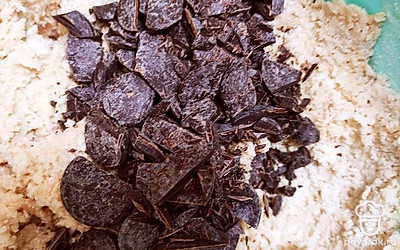 Порубить шоколад. Добавить мучную смесь к масляно-яичной, быстро смешать до объединения. Вмешать шоколад. 