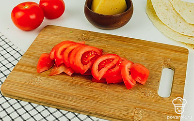 Нарежьте тонкими дольками помидор.