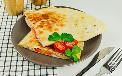 Подавайте закуску из лаваша со свежей зеленью и помидорами.