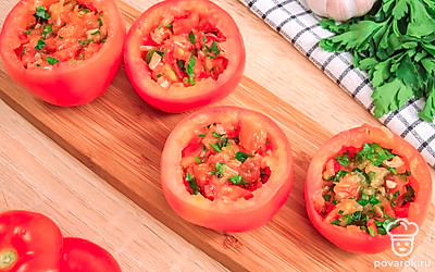 Смешайте начинку с нарубленной петрушкой и наполните ею помидоры.
