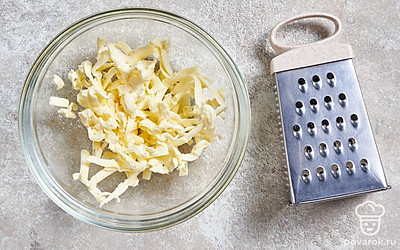 Застывшее до твердого состояния масло достаньте из морозильной камеры и натрите его в миску на крупной или средней терке.