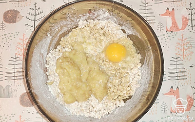 В овсяно-мучную смесь добавьте растопленное сливочное масло, банановое пюре и яйцо.