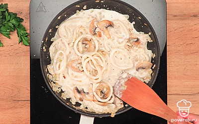 Поставьте на плиту сковороду, смажьте ее растительным маслом. Обжаривайте грибы на среднем огне 15 минут. Отложите шампиньоны на отдельную тарелку. На ту же сковороду выложите лук, обжаривайте 5 минут. Добавьте к луку кальмаров. Обжаривайте 1 минуту. Небольшой струйкой влейте сливки, постоянно помешивая. Добавьте сыр и чеснок, хорошо перемешайте. Убавьте огонь до минимального. Положите в соус обжаренные грибы, соль и специи. Перемешайте, накройте крышкой и тушите 2 минуты.