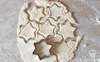 Тесто достаньте из холодильника, раскатайте в пласт и вырежьте формочкой печенье. 