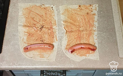 Лаваш разрежьте на широкие полоски. Майонез и кетчуп смешайте, смажьте соусом лаваш. На край лаваша выложите обжаренные сосиски.