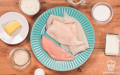 Удобно расположите все ингредиенты. Отварите яйца и очистите от скорлупы. Разморозьте тушки кальмара, вымойте и очистите от пленочек. Филе индейки вымойте и промокните бумажным полотенцем. В подсоленной воде сварите рис. Отварите филе индейки. Порежьте индейку на мелкие кубики. На среднюю терку натрите яйца. Сыр натрите на терке. Приготовьте жаропрочную форму. Разогрейте духовку до 180 градусов.