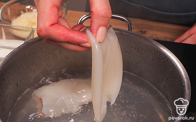 Отварите тушки кальмаров. Закипятите в кастрюле воду, опустите кальмары на 2 минуты, достаньте и дайте остыть.