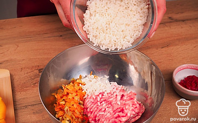 Приготовьте начинку для перцев. Обжарьте морковь и лук на сковороде с добавлением растительного масла в течение 5 минут. Добавьте шампиньоны на сковороду. Смешайте рис, обжаренные овощи, фарш и специи.