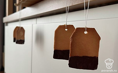 Тесто раскатать. Взять чайный пакетик любого чая, обвести ножом пакетик по контуру, и так сделать много печенюшек, трубочкой от сока сделать дырочку, поставить в духовку, нагретую до 200, выпекать 10-15 минут. После того как печенье остынет, привязать веревочки с ярлычками, обмакнуть в растопленный шоколад и повесить сушить.