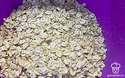 Смешать в одной емкости овсяные хлопья молоко, сахар и изюм. Яйца взбить и добавить в полученную смесь.