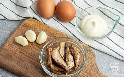 Отварите яйца в течение 10 минут и очистите от скорлупы. Разрежьте яйца пополам, выньте желток и положите его в отдельную посуду. Подготовьте 3 зубчика чеснока и шпроты.