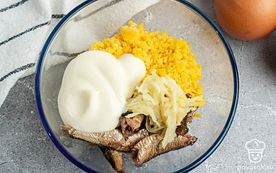 Добавьте к желткам шпроты, измельченный чеснок и майонез. Хорошо перемешайте.