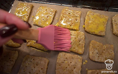 Взбейте желток с молоком и смажьте крекеры.