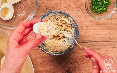 Приготовьте начинку и нафаршируйте яйца. Соедините сыр, измельченный чеснок и желток, майонез, жареные с луком шампиньоны. Посолите по вкусу. Хорошо перемешайте до однородной массы. Наполните половинки белков начинкой.