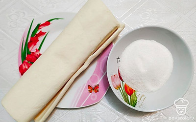 Тесто заранее достаньте размораживаться из морозильной камеры. Противень застелите бумагой для выпечки.