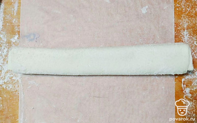 Если необходимо, то раскатайте тесто до толщины 3 сантиметра. Присыпьте его сахаром, немного вдавливая скалкой. Визуально поделите пласт на 4 части. Две крайние из них подогните к центру, чтобы края практически соприкасались, а после вновь сложите половинки, тем самым получив три слоя с каждой стороны.