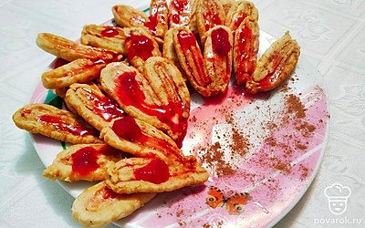 Готовое печенье выложите на большую тарелку, полейте любимым вареньем или джемом и посыпьте какао. Подайте к столу с теплым напитком.