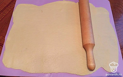 Тесто раскатайте в большой пласт. В миске смешайте сахар и корицу. Тесто смажьте растопленным сливочным маслом и равномерно посыпьте корицей с сахаром. Скатайте рулет, порежьте на 2 части и отправьте на 10 минут в морозилку.