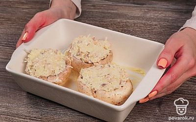 Приготовьте грибы. Отделите ножки от шляпок. Шляпки оставьте целыми, ножки мелко покрошите. На дно жаростойкой посуды для микроволновки положите сливочное масло. Смешайте измельченные грибы, сыр, чеснок, майонез и соль. Перемешайте ингредиенты. Наполните смесью шляпки грибов. Выложите в посуду для запекания. Готовьте в микроволновке 10 минут на максимальной мощности.