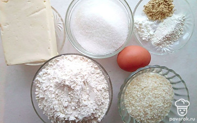 Распакуйте маргарин. Насыпьте сахар, кокосовую стружку и муку по разным тарелкам. Подготовьте разрыхлитель, имбирь и ванилин.