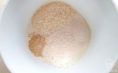 Возьмите глубокую миску и всыпьте в нее муку. Добавьте 50 грамм кокосовой стружки, имбирь, разрыхлитель и ванилин. Перемешайте сухие ингредиенты.