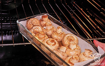 Приготовьте шампиньоны. Залейте грибы маринадом. Накройте пищевой пленкой и оставьте на 120 минут. Противень застелите пергаментом. На него выложите замаринованные грибы шляпками вниз. Запекайте маринованные грибы в духовке, разогретой до 190 ˚C, 35 минут.