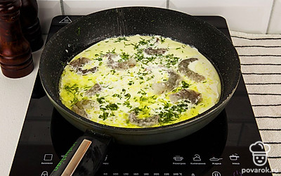 Добавьте в сковороду сливки и зелень. Все хорошо перемешайте и добавьте очищенные креветки. Посолите и поперчите блюдо по своему вкусу.