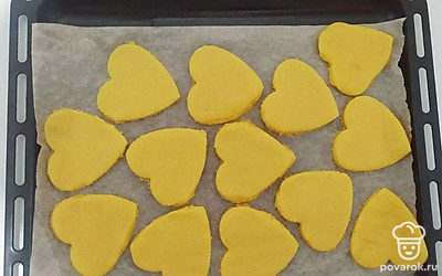 Достаньте тесто из холодильника и раскатайте на столе, присыпанном кукурузной мукой. При помощи формочек вырежьте из теста заготовки для печенья и переложите их на противень, застеленный пергаментом. Выпекайте печенье в духовке при 180 градусах около 15 минут.