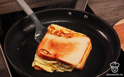 Сформируйте сэндвич. Для этого одну из сторон омлета приподнимите с нижней стороны и одним движением сложите пополам. Аккуратно переложите на тарелку, разрежьте по диагонали на две половинки и наслаждайтесь. Приятного аппетита!