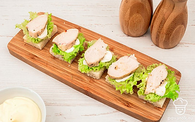 На каждый ломтик хлеба положите по небольшому кусочку листового салата. Сверху на салат положите немного майонеза и по ломтику курицы.