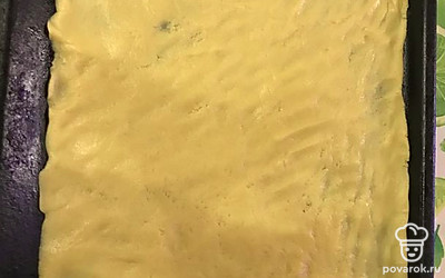 Остальную часть теста разложите на противень. Удобнее это делать руками. Сверху смажьте джемом а наверх на крупной терке натрите оставшееся тесто из холодильника.