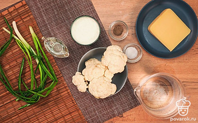 Кочан капусты хорошо промойте под проточной водой, обсушите бумажным полотенцем и разберите на соцветия. Натрите сыр на крупной терке. Форму для запекания смажьте растительным маслом. Разогрейте духовку до 200 ℃. Помойте, обсушите и мелко нарежьте перья зеленого лука.