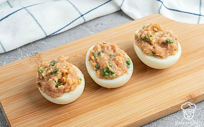 Выложите начинку в яичный белок, разрезав его пополам.