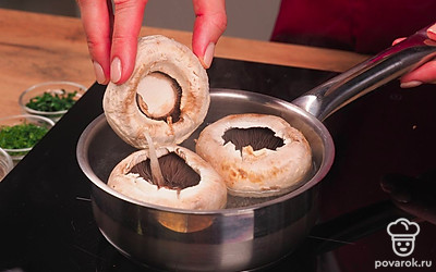 Подготовьте грибы. Шляпки шампиньонов проварите 7-10 минут в подсоленной воде, достаньте и положите на тарелку шляпкой вверх, чтобы вытекла лишняя вода.