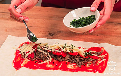 Соберите шаурму. Разложите лист лаваша, с краю положите ложку томатного соуса и размажьте его, добавьте 2-3 ложки фарша. На него выложите дольки помидора и присыпьте все тертым сыром. Сверху посыпьте зеленью по вкусу и положите пару ложек томатного соуса. Плотно заверните начинку в лаваш.