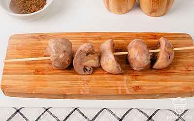 Включите духовку, чтобы она успела разогреться и вернитесь к грибам. Достаньте их из маринада и нанизывайте на шпажки - на каждой свободно помещаются 4-6 половинок шампиньонов.