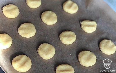 Полученное тесто разделите на маленькие кусочки, сформируйте из них шарики, которые затем сплюсните и выложите на противень, застеленный пергаментом. Слегка посыпьте печеньки сахаром.