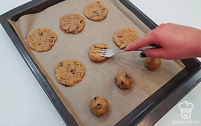 Сформируйте из получившегося теста шарики, размером примерно с грецкий орех, и выложите на противень, застеленный пергаментом. Не кладите заготовки близко друг к другу, потому что при выпечке печенье увеличится в размере. При помощи вилки, путем надавливания, придайте печенью плоскую форму.