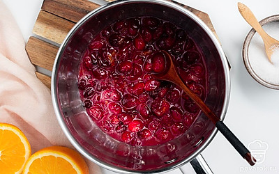 Приготовьте клюквенный джем. В сотейник выложите клюкву, крахмал, половину сахара и цедру апельсина. Поставьте на средний огонь и доведите до кипения. Уменьшите огонь и варите 10 минут до загустения. Снимите сотейник с огня.